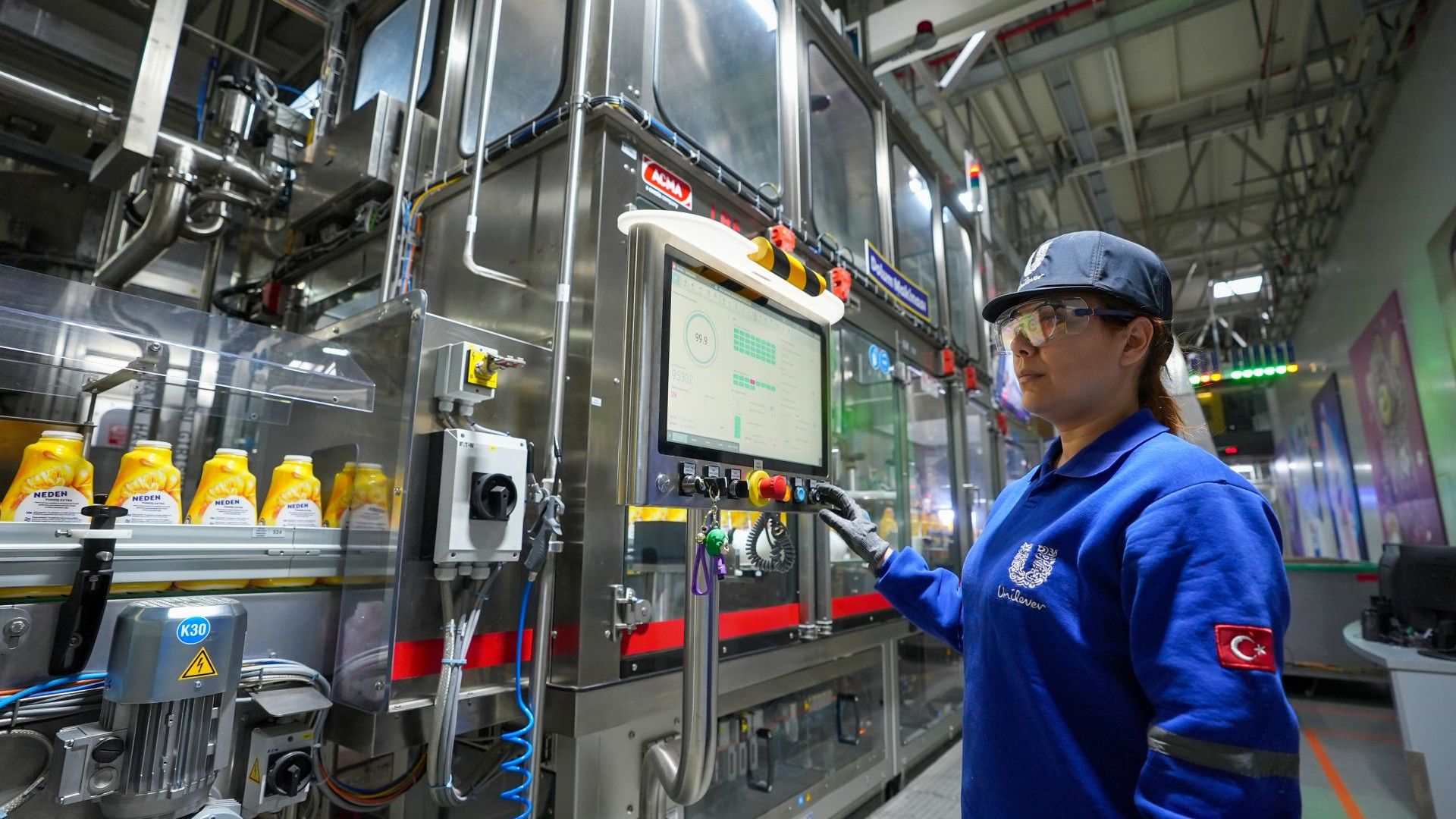 Üzerinde Unilever logosu bulunan üniforma giymiş bir fabrika işçisi.