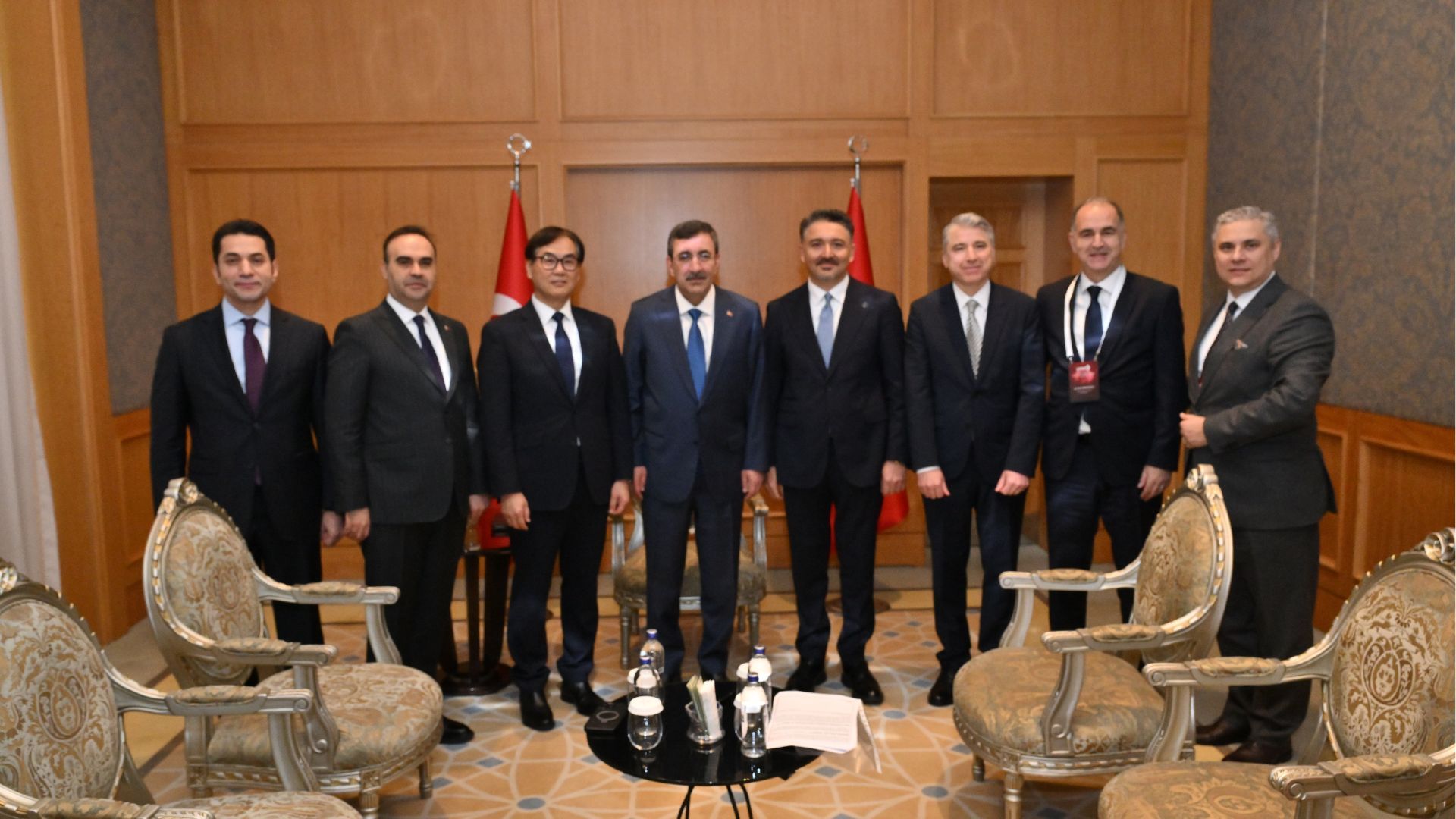 Toplantı odasında takım elbise giymiş sekiz adam görüldü.