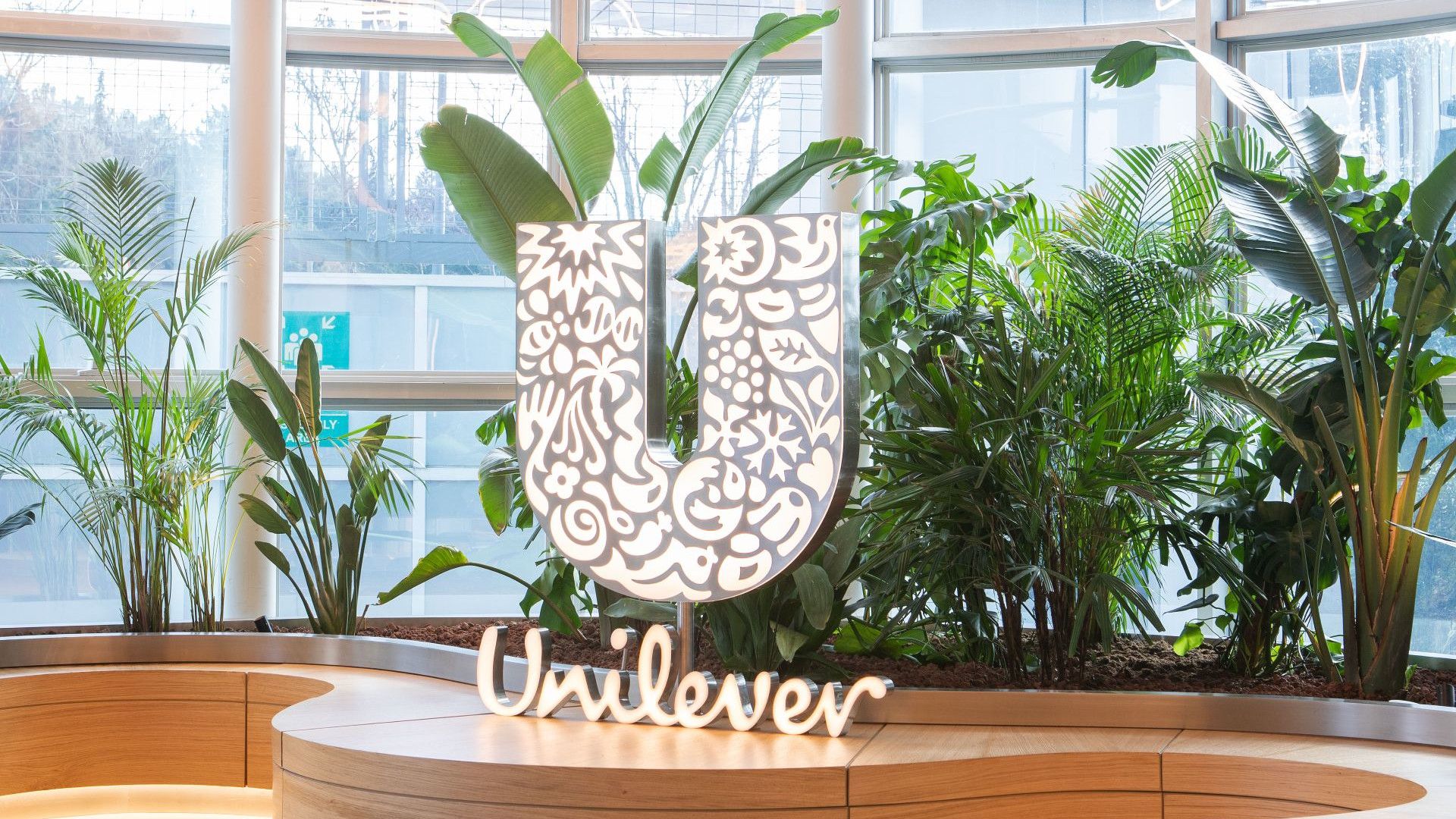 Bir binanın içinde, bitki örtüsünün önünde Unilever logosu.